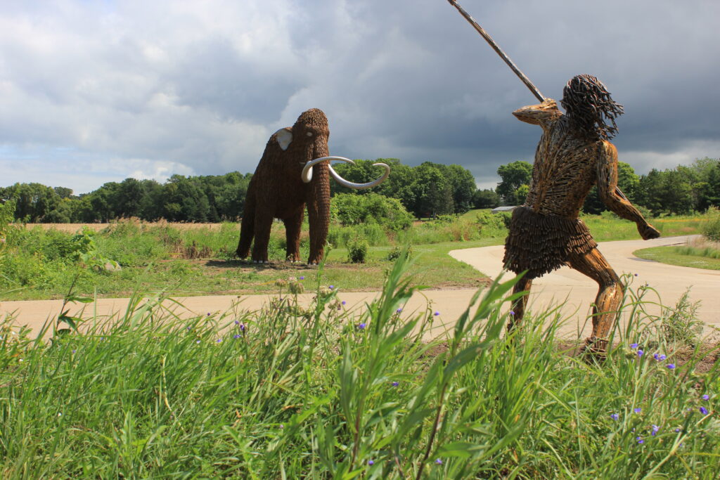 outdoor sculpture of a hunter and a mammoth made of metal