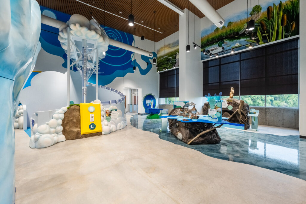 Room view of multiple bright exhibits, including nature-styled areas