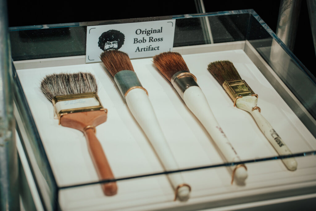 an artifact case with four paint brushes use by Bob Ross