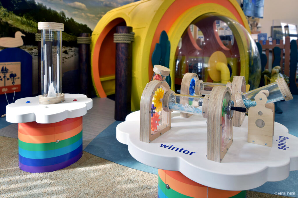 Custom-designed and fabricated themed play space featuring a walk-through submarine and two STEAM tables.