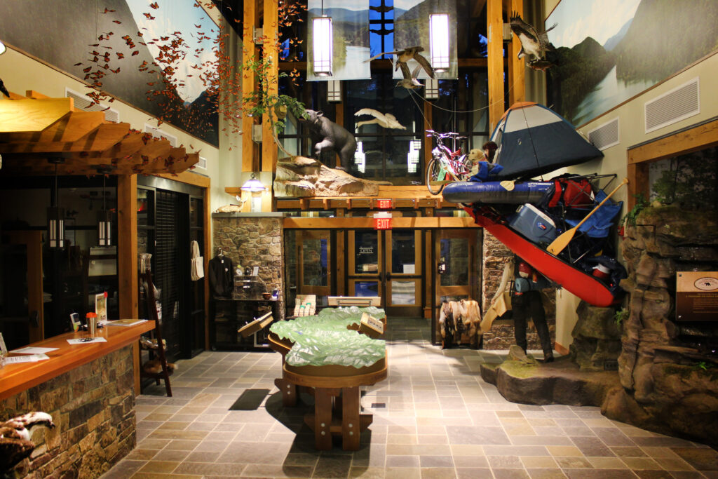 Entrance view with a topographic map in the middle, a tower of camping gear on the right, and looking up shows a variety of bird models and a bear model