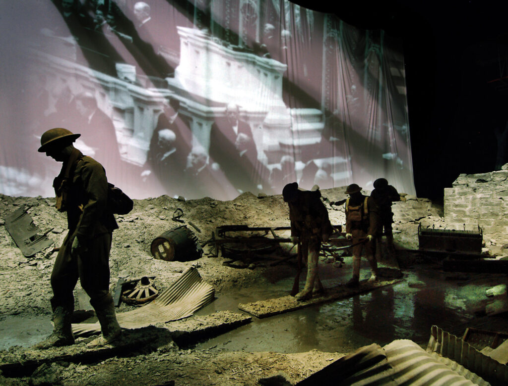 soldier figures walking through debris with a screen in the background playing an educational video