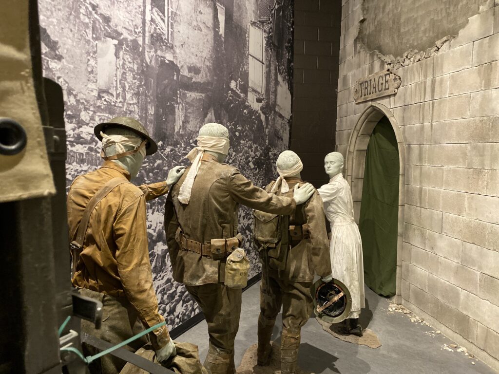 three blindfolded figures walking towards a fourth figure near a triage sign