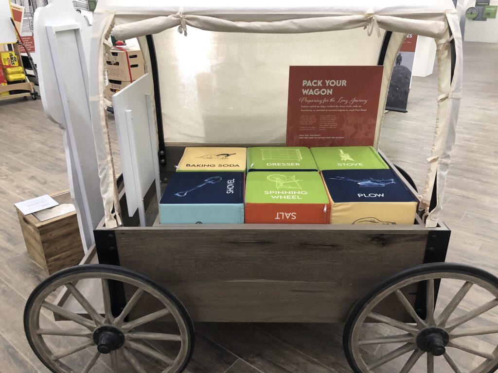 A custom-made, interactive exhibit at Fort Bend Museum that looks like a wagon. A sign says pack your wagon.